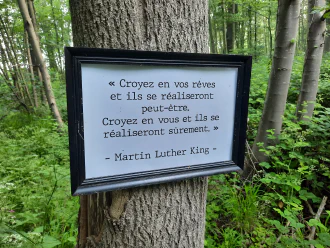 A sign on a tree cites Martin Luther King in French: “Croyez en vos rêves et ils se réaliseront peut-être. Croyez en vous et ils se réaliseron sûrement.”