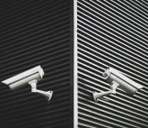 Two security cameras mounted on the walls of a building